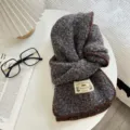 Detail view of cozy textured knit scarf with brown trim and woven label on white table. - 156x22 / Dark Gray Style (04#)