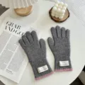 Detail view of warm grey knit gloves featuring pink cuffs and chic labels for winter daily wear. - One Size / Gray