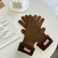 Detailansicht brauner Winter-Strickhandschuhe mit kuscheligen Plüschbündchen und rosa Label-Akzenten. - Braun (05#)