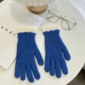 Blue knit gloves detail shot featuring white ribbed cuffs laid flat on white table decor. - Blue