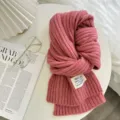 Nahaufnahme eines kuscheligen rosa Rippstrick-Winterschals mit Etikett, eleganter Stil. - Rosa