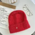 Red fluffy knit beanie with shimmering threads and metal tag detail, cozy winter accessory. - One Size / Red