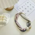 Close-up detail of elegant pearl silk scarf with floral pattern and decorative pendant. - Necklace Without Pearl / Pearl Scarf-2