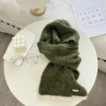 Vue detaillee de l'echarpe en tricot bicolore vert fonce avec une texture douce et un ourlet. - Vert Foncé