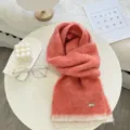 Gros plan détaillé d'une écharpe en tricot bicolore corail rose à texture douce et étiquette chic. - Pêche