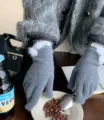 Gedetailleerd overzicht van grijze gebreide wol winterhandschoenen met witte zachte pompons. - donkergrijs