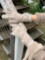 Gedetailleerde close-up van gebreide wollen handschoenen met schattige bontpompons. - Beige