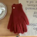 Gros plan de gants tricotés rouges avec volants et bouton en métal sur fond bois. - 23cm x 8cm / Rouge