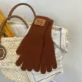Detail view of brown knitted long gloves with a stylish patch, soft texture for winter warmth. - Coffee