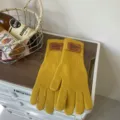 Detailed view of winter warm yellow knitted five-finger long gloves with leather label. - Sunset Yellow