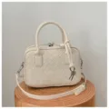 Close-up detail of cream woven leather handbag with stylish knot strap and double top handles. - Off White
