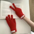 Primer plano detallado de guantes táctiles de punto rojo vivo con elegante parche de letras. - Rojo