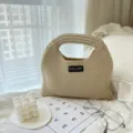 Detailansicht der beige Strickhandtasche mit feiner Textur in gemütlicher Schlafzimmeroptik. - S / Aprikose