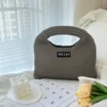 Nahaufnahme einer grauen Strickhandtasche mit strukturierter Webung und Etikett im Wohnstil. - S / Mokka