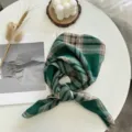 Gros plan d'un carré de soie en coton à carreaux vert et kaki stylisé sur table blanche. - Ligne Carré Vert