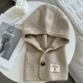 Gekneteter Kapuzenschal Detailansicht mit Knopfverschluss und gewebtem Etikett in beige cozy - Beige