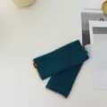 Detail view of dark green knit fingerless gloves featuring contrasting beige edges and cozy texture. - One Size / Lake Blue