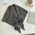 Detailed shot of a black floral print triangle scarf waist wrap draped on white textured fabric. - Black Floral Style / 140*70cm