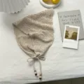 Primer plano de pañuelo triangular de punto calado beige con cordón y borlas de cuentas. - Talla única / Té con leche