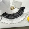 Detailed shot of a black and white plaid fake hem skirt with white lace embroidery trim and side ties. - Bottoms / One Size / Black