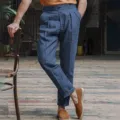 Detailed view of men's casual linen trousers featuring pleated design and relaxed fit scene. - Blue