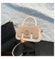 Detailansicht der stilvollen Kontrast-Handtasche mit Metall-M-Logo und Laschendesign. - Gebrochenes Weiß