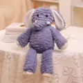 Vista detallada de un simpático elefante de peluche morado con tela texturizada y orejas grandes. - Elefante