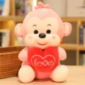 Close-up detail of a cute pink plush monkey holding a red heart pillow with love embroidery. - Heart Holding Monkey / 20cm / Pink