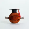 Primo piano dettagliato di un peluche da basket carino con cappello di laurea e sorriso. - Basket