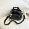 Dark denim Boston bag with top handles, crossbody strap, front pocket and pearl charm. - Black With Pendant