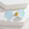 Detailaufnahme von hellblauen Glitzer Kuppel Ohrringen mit Goldverschluss auf Steinen. - Blau