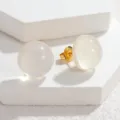 Nahaufnahme von weißen glitzernden runden Ohrsteckern auf weißem geometrischem Display Stand. - Weiß