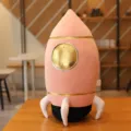 Detailed view of the cute pink rocket plush toy with gold accents, soft texture and cozy pillow design. - Pink Spaceship