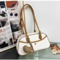 Close-up of stylish white and brown shoulder baguette bag with cute knitted heart pendant charm. - Cream White With Pendant