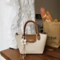 Stylish canvas handbag with brown leather flap, top handle and cute flower charm for daily use. - With Charm / Off White