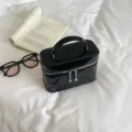 Black quilted vanity bag with top handle and metal ball zipper, chic cosmetic shoulder bag. - Black