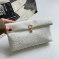 Stylish women's white woven clutch bag with unique rolled design and metallic closure for daily use. - White