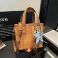 Detailed shot of brown canvas bucket bag with silver star charm and leather chic strap. - Brown