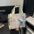 Detailaufnahme einer schicken Beigefarbenen Canvas Tasche mit silbernem Sternanhänger. - Mit Anhänger / Weiß