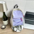 Small casual nylon backpack with purple front pocket and blue bungee cord for daily travel. - Purple