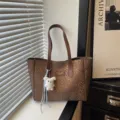Braune Damen Beuteltasche mit Leo-Muster, große Pendler Umhängetasche mit süßem Plüsch-Anhänger. - Mit Anhänger / Braun