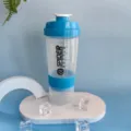 Detailed view of the clear 3-layer protein shaker bottle with blue lid and storage compartment. - Sky Blue