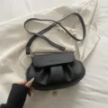 Schwarze Leder-Umhängetasche für Damen, stilvolles Plissee-Satteldesign mit verstellbarem Gurt. - Schwarz
