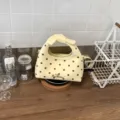Dettaglio della borsa a mano gialla a pois con manico a fiocco, perfetta per outfit primaverili. - Giallo