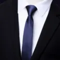 Detail view of a stylish narrow navy blue tie paired with white shirt and black suit for men. - Arrow-Shaped / 5cm / Navy Blue