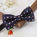 Gros plan d'un nœud papillon bleu foncé avec motif floral blanc et orange pour costume. - Nœud Papillon Petites Fleurs Jaunes