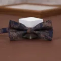 Close-up detail of a navy blue bow tie featuring intricate golden floral patterns. - Night Golden Branch
