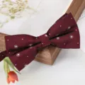 Grosplan détaillé de nœud papillon bordeaux à motifs pois blancs sur support en bois naturel. - Nœud Papillon Cercle Concentrique Rouge Vin