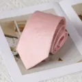 Close-up detail of a stylish pink textured men's necktie neatly rolled on a magazine surface. - 8cm Handmade Style / Rouyunxian Light Pink