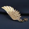 Detailaufnahme der goldenen Flügel-Brosche mit feiner Federstruktur und kleinem Schlüssel. - Goldene Elfenflügel Brosche